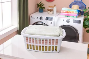 Hamper full of sheets on top of laundry counter with washer and dryer in background